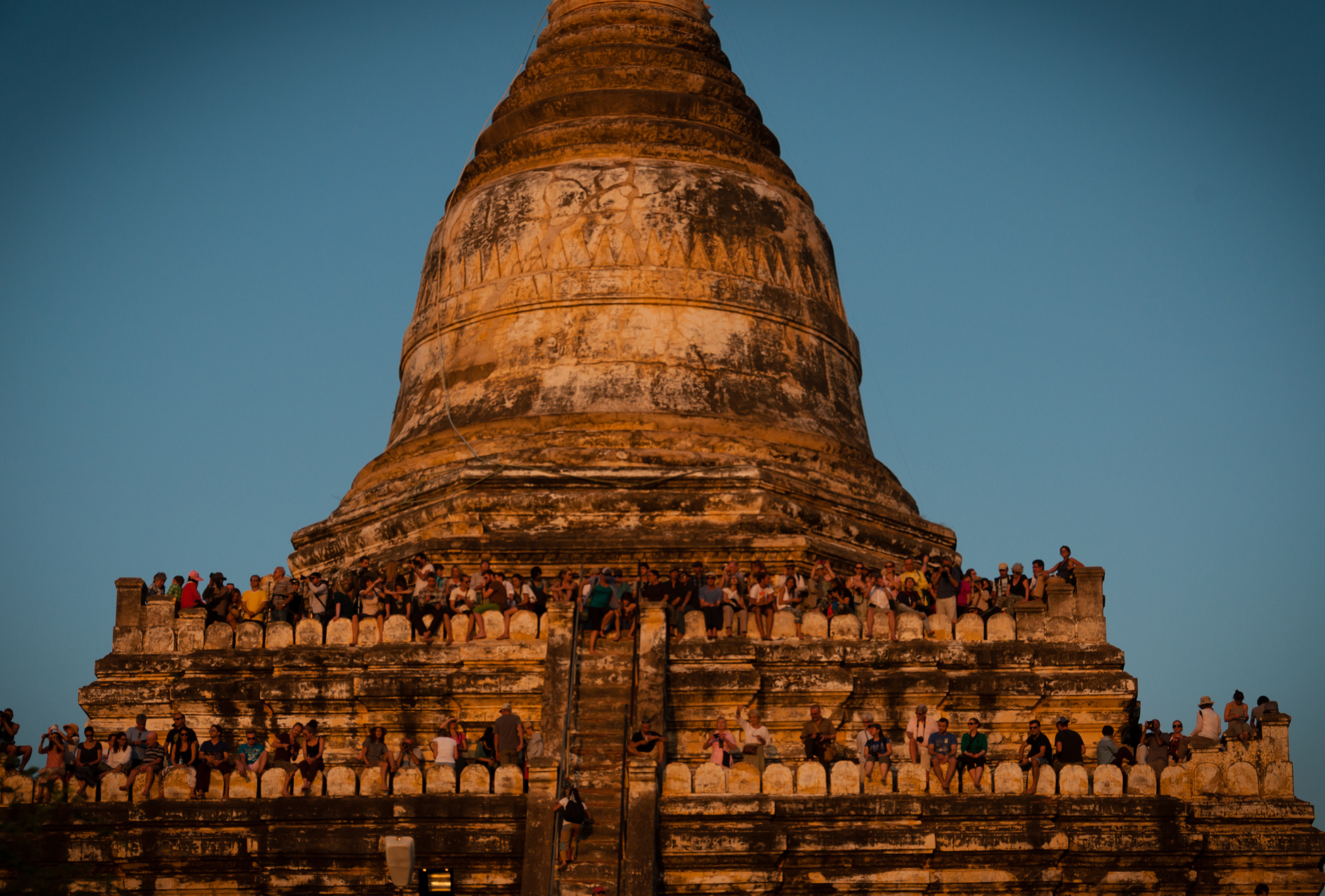 People observing from the terraces of the Shwesandaw Pagoda with a clear blue sky in the background